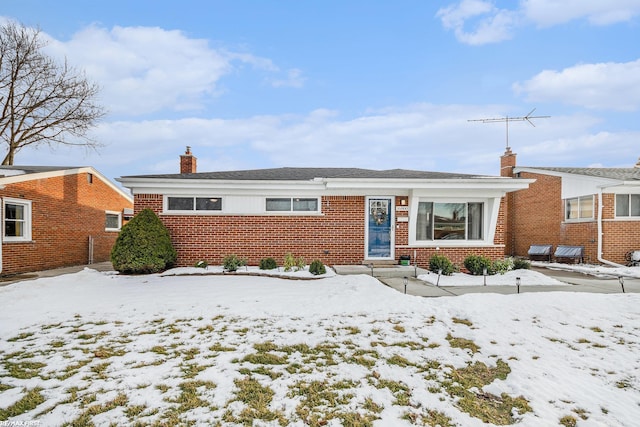 ranch-style home with entry steps, a chimney, and brick siding