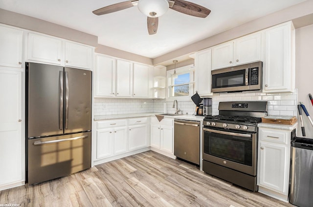 kitchen with appliances with stainless steel finishes, pendant lighting, light countertops, and white cabinetry