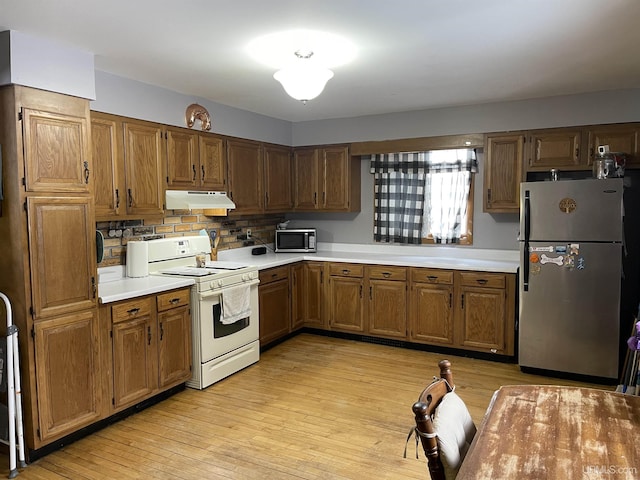 kitchen with under cabinet range hood, appliances with stainless steel finishes, light countertops, and light wood finished floors