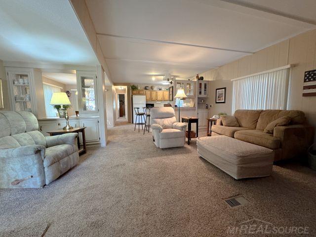 living area with beamed ceiling and carpet flooring