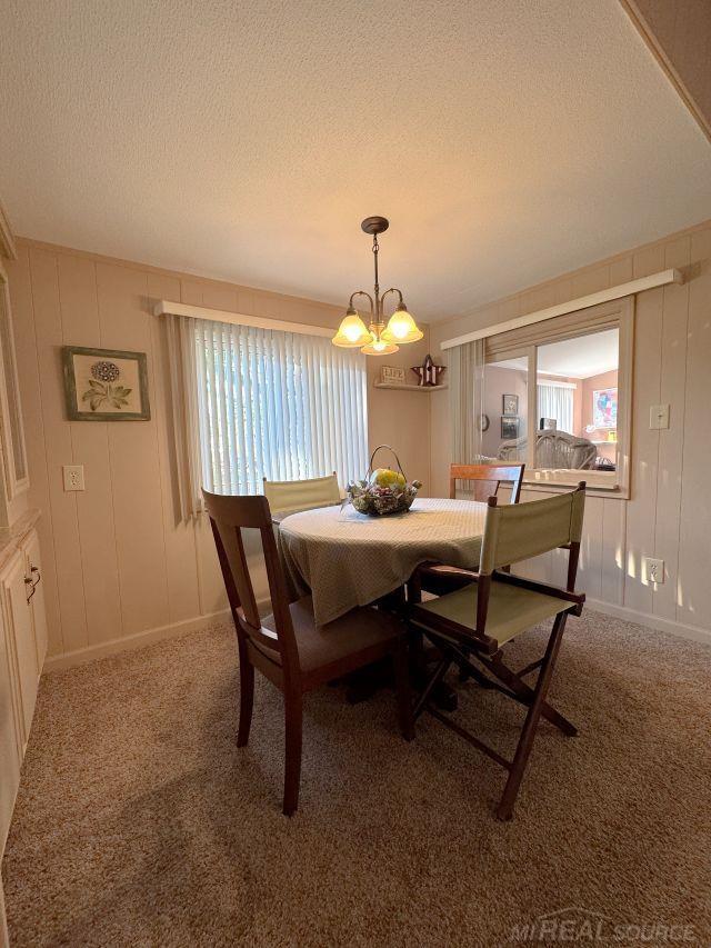 dining area with carpet floors, a chandelier, and a textured ceiling