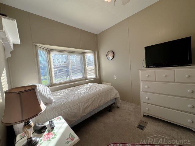 carpeted bedroom featuring lofted ceiling and visible vents