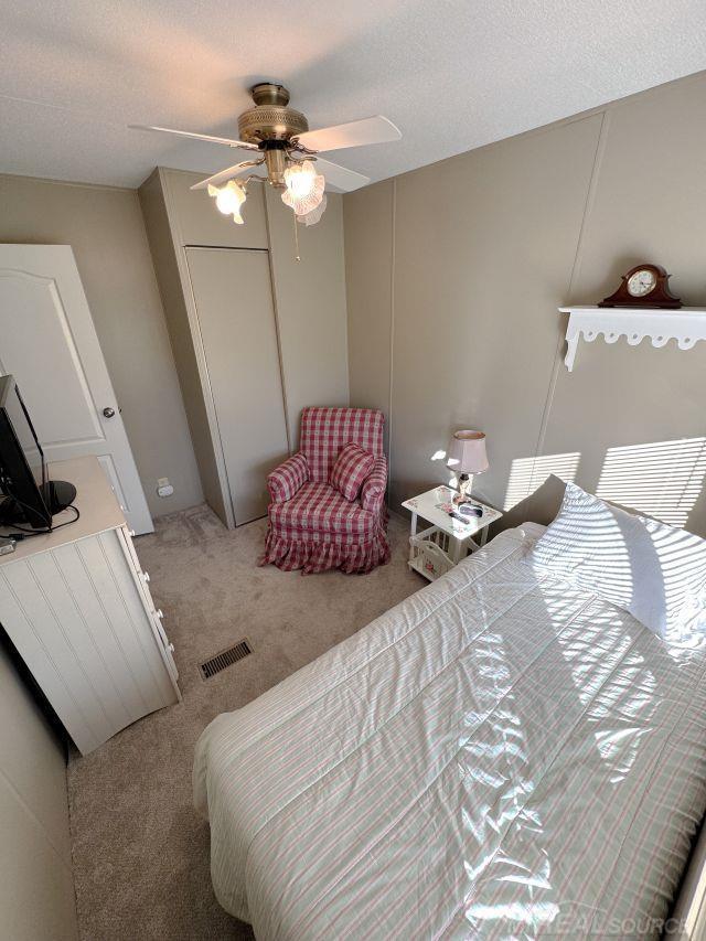 bedroom featuring visible vents, a ceiling fan, carpet, a textured ceiling, and a closet