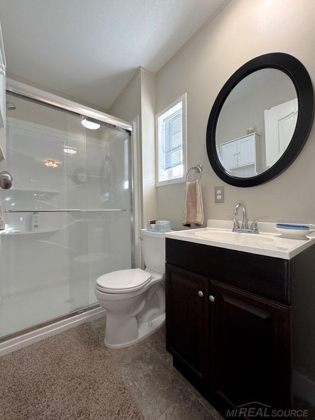 full bathroom with a stall shower, vanity, and toilet