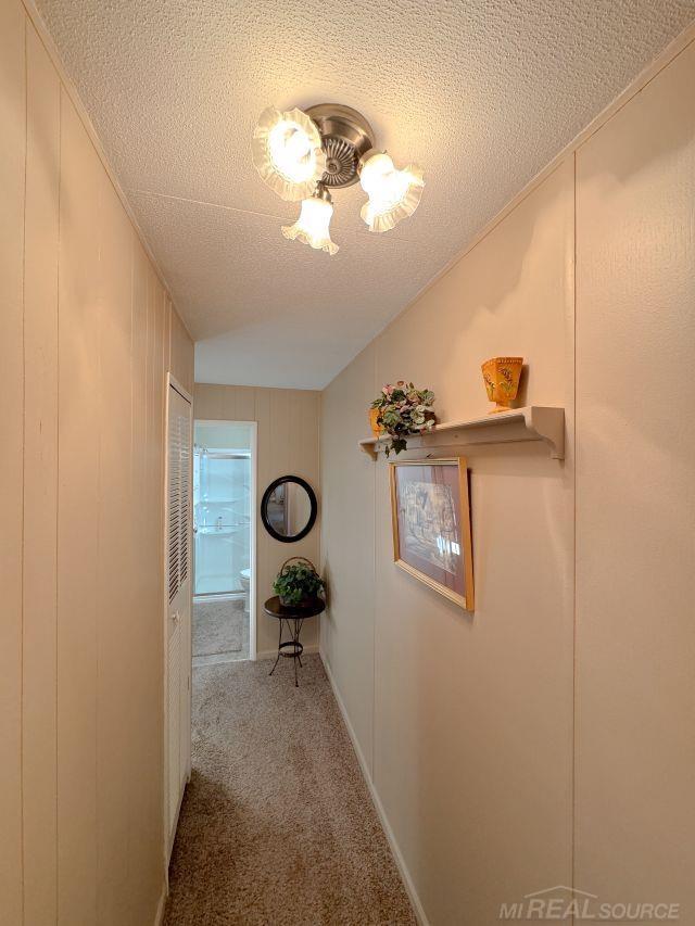 corridor with a textured ceiling and carpet flooring