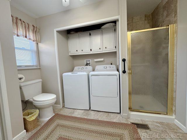 bathroom with toilet, a stall shower, visible vents, and washer and dryer