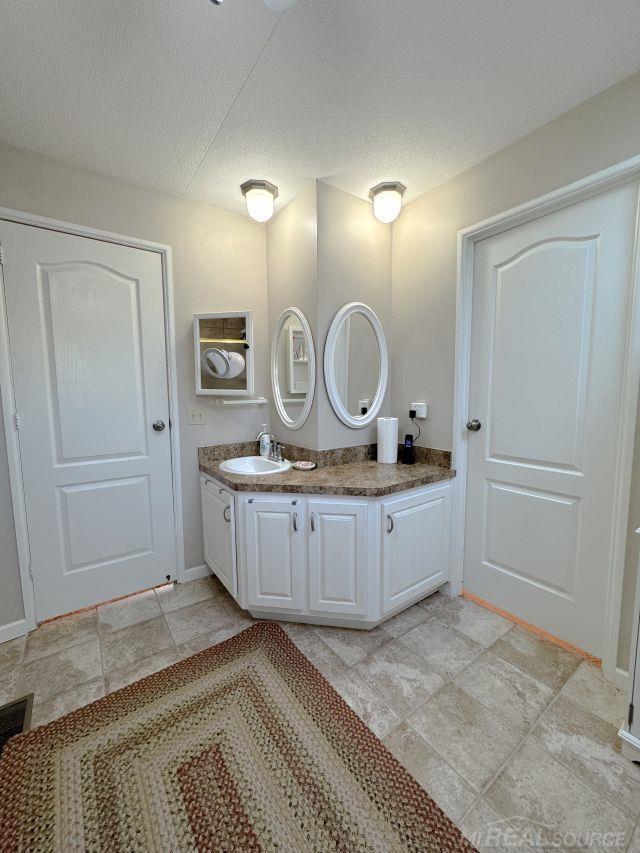 bathroom featuring baseboards, a textured ceiling, and vanity