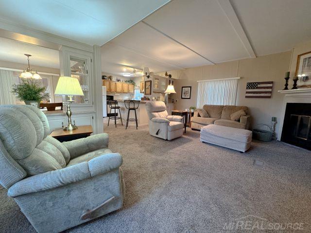 living room featuring carpet floors, a chandelier, and a glass covered fireplace