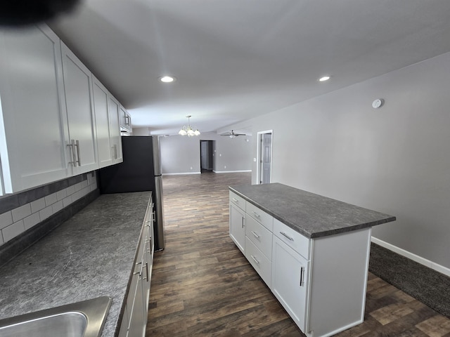 kitchen featuring a center island, decorative light fixtures, dark countertops, open floor plan, and white cabinets