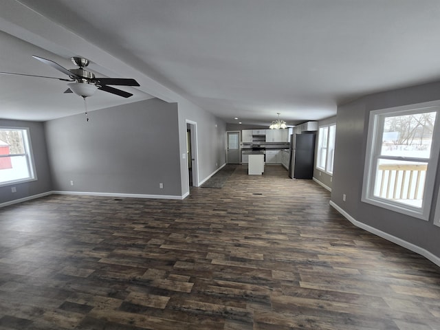 unfurnished living room with baseboards, dark wood-style flooring, and ceiling fan with notable chandelier