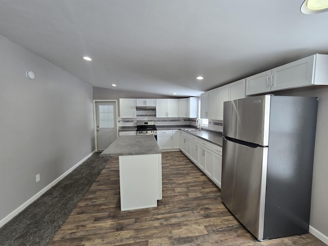 kitchen with a sink, white cabinetry, appliances with stainless steel finishes, a center island, and dark countertops