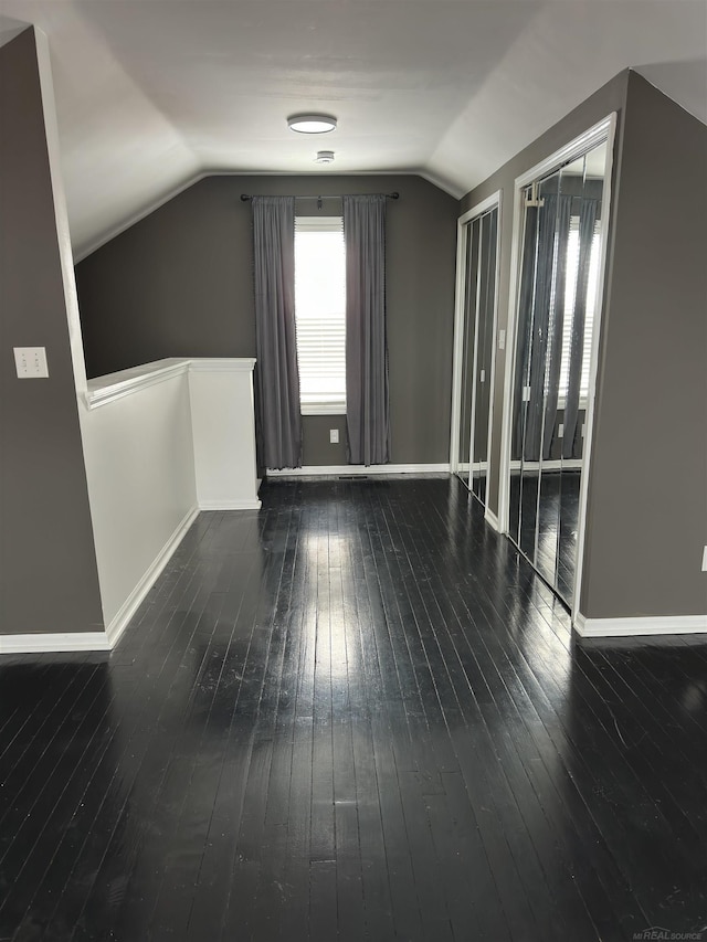 bonus room featuring vaulted ceiling, dark wood-type flooring, and baseboards