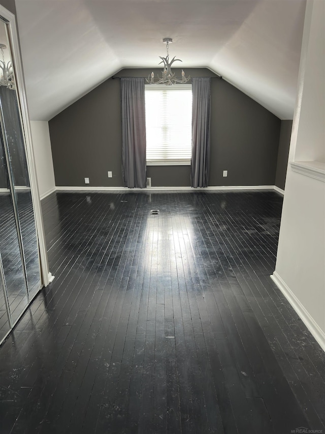 additional living space featuring dark wood-style floors, vaulted ceiling, and baseboards