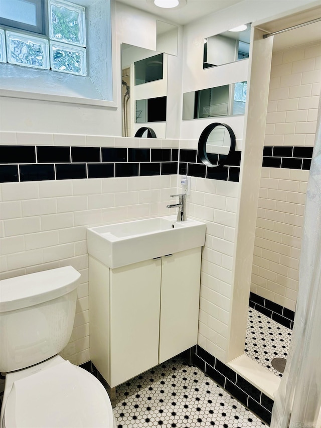 full bath featuring a stall shower, vanity, toilet, and tile walls