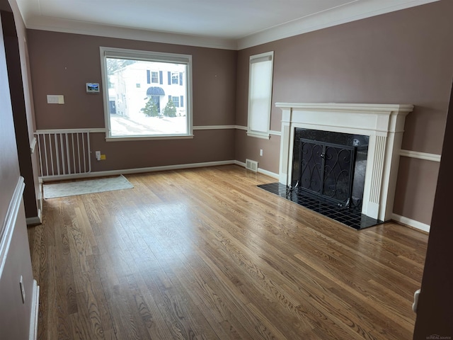 unfurnished living room with light wood-style flooring, a fireplace with flush hearth, visible vents, and baseboards