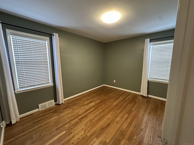 unfurnished room with visible vents, baseboards, and wood finished floors