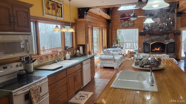 kitchen featuring white appliances, a fireplace, a sink, open floor plan, and hanging light fixtures