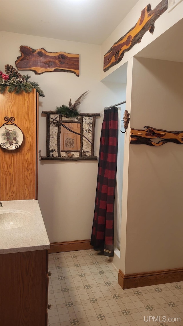 bathroom with curtained shower, vanity, baseboards, and tile patterned floors