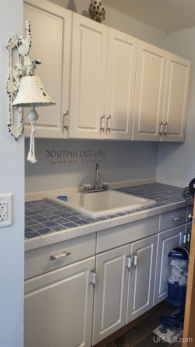 kitchen with tile countertops, white cabinets, and a sink