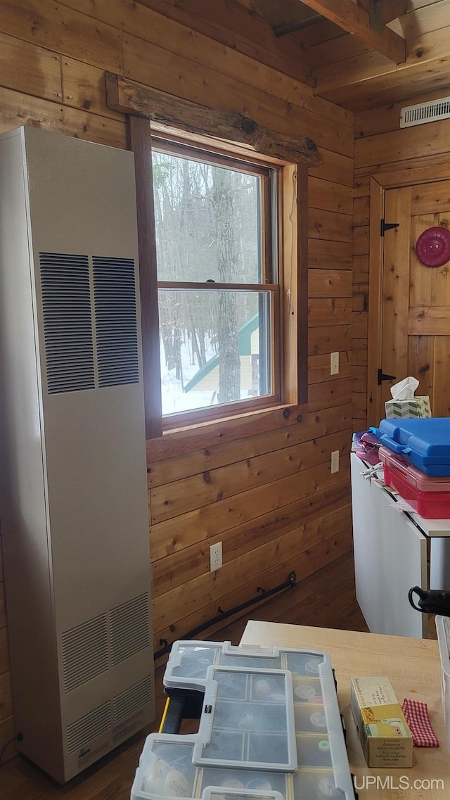 interior space with wood walls, a heating unit, and visible vents