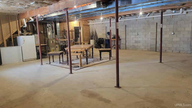 unfinished basement featuring freestanding refrigerator, refrigerator, and heating unit