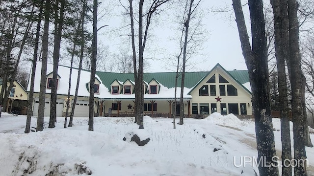 snow covered property featuring a garage and a porch