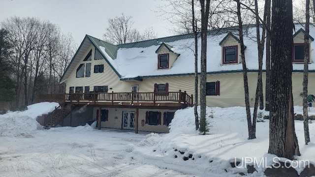 snow covered rear of property with a deck and stairs