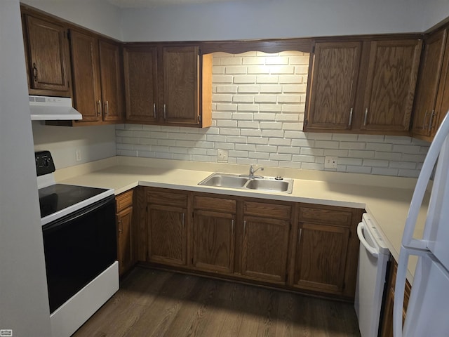 kitchen with white appliances, under cabinet range hood, light countertops, and a sink