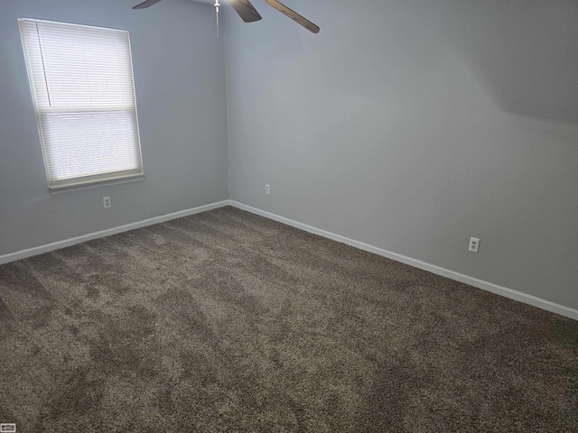 empty room featuring baseboards, dark carpet, and ceiling fan