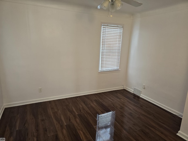 empty room featuring ceiling fan, dark wood finished floors, visible vents, and baseboards