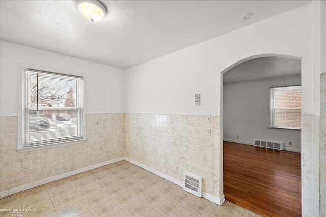 spare room featuring plenty of natural light, arched walkways, and visible vents