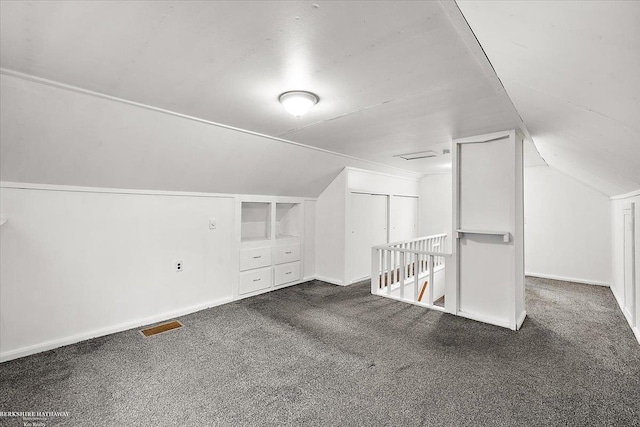 bonus room with lofted ceiling, visible vents, dark carpet, and baseboards