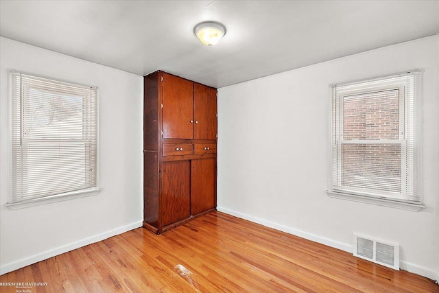 unfurnished room with light wood-type flooring, a healthy amount of sunlight, baseboards, and visible vents