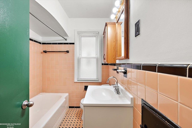 bathroom featuring a bathtub, wainscoting, vanity, and tile walls