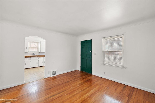 empty room with light wood-type flooring, visible vents, and baseboards