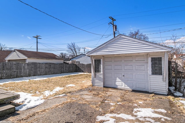 detached garage featuring fence and driveway