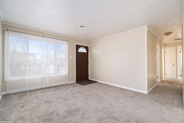 foyer entrance featuring light carpet, crown molding, and visible vents