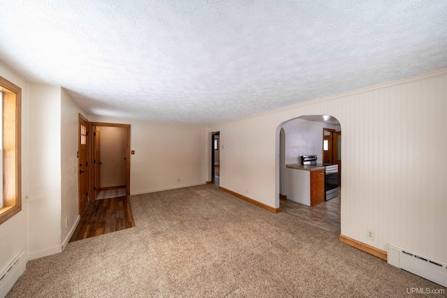 spare room with a baseboard heating unit, a textured ceiling, light carpet, and arched walkways