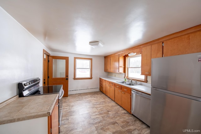 kitchen featuring stainless steel appliances, a sink, light countertops, baseboard heating, and brown cabinetry