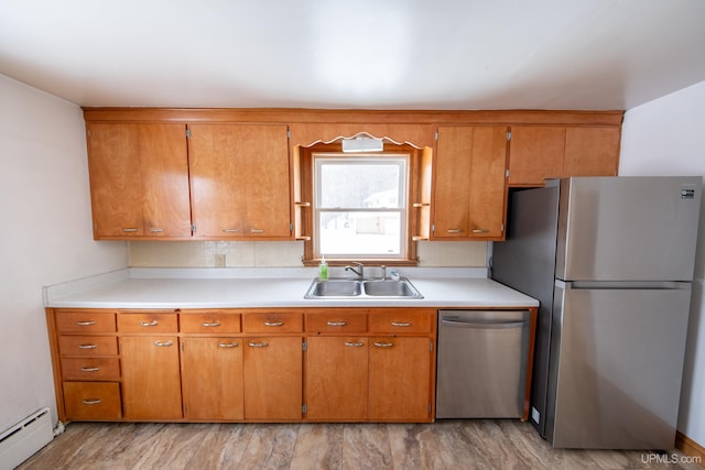 kitchen with baseboard heating, stainless steel appliances, a sink, and light countertops