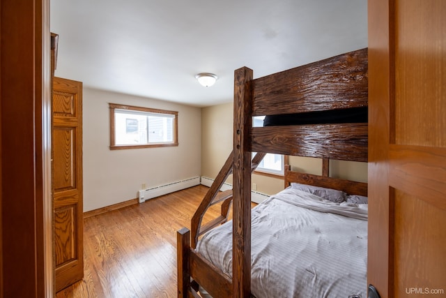 bedroom with baseboards, a baseboard radiator, and light wood-style floors