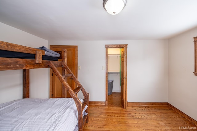 bedroom featuring light wood-style floors, a spacious closet, baseboards, and a closet