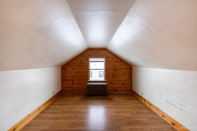 additional living space with radiator, dark wood-style floors, baseboards, and vaulted ceiling