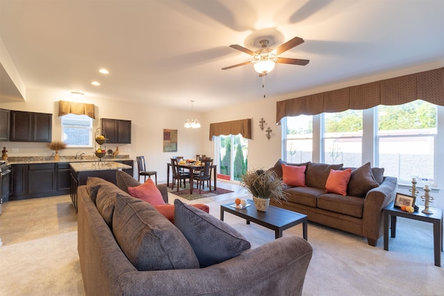 living area featuring ceiling fan with notable chandelier, recessed lighting, and light colored carpet