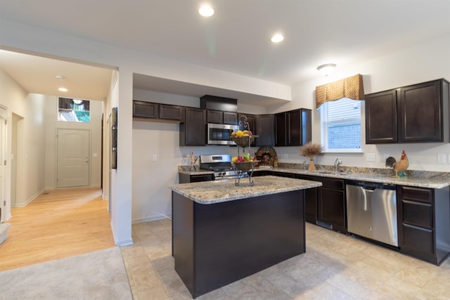 kitchen featuring light stone counters, stainless steel appliances, recessed lighting, a kitchen island, and dark brown cabinets