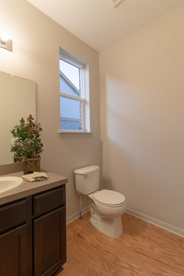 bathroom with baseboards, vanity, toilet, and wood finished floors