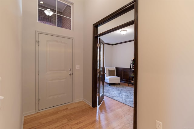 foyer featuring ornamental molding, light wood-type flooring, and baseboards