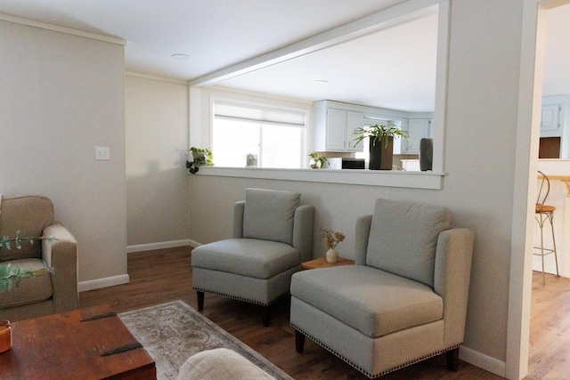 living area featuring crown molding, baseboards, and wood finished floors