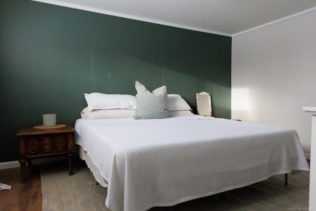 bedroom with ornamental molding and wood finished floors