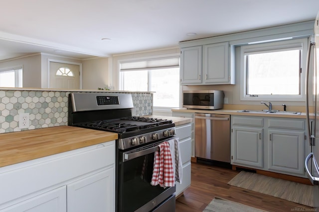 kitchen featuring stainless steel appliances, decorative backsplash, a sink, and white cabinets